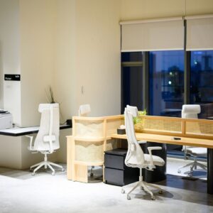 Wide shot of empty contemporary coworking office interior with shared desks, ergonomic chairs and city view at night